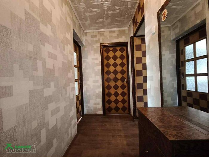 Hallway with mismatched patterned walls and doors in a wild real estate listing unusual interior design.