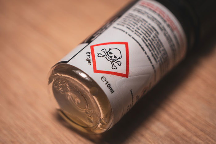 Close-up of a small bottle with a danger symbol, highlighting toxic contents and cautionary family drama discussion online.