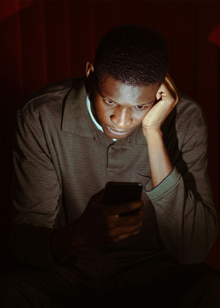 Man looking at smartphone in dim light, reflecting on red flags that could mean someone is a narcissist. Man looking at smartphone in dim light, reflecting on red flags that could mean someone is a narcissist.