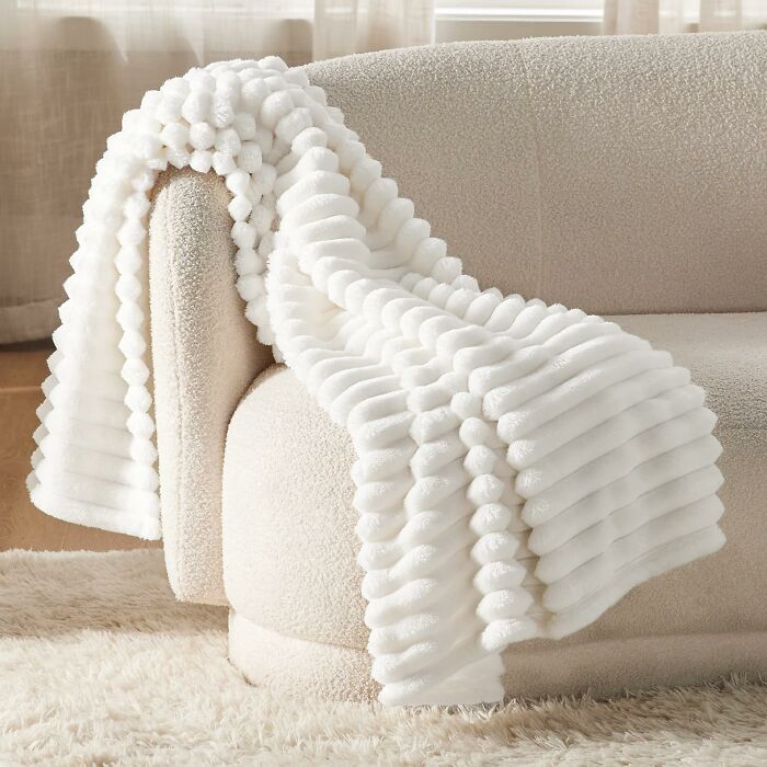 Soft white textured throw blanket draped over a cozy cream sofa enhancing warm home comfort and cozy finds.