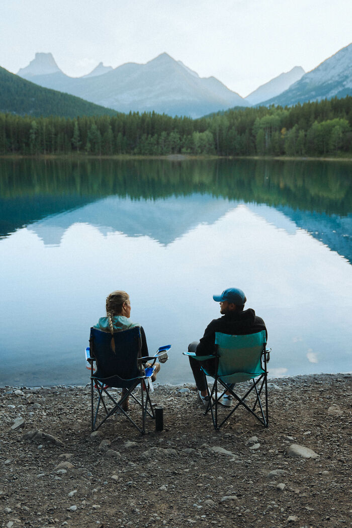 Two people sitting by the lake in camping chairs with mountain reflections, symbolizing a journey toward finding purpose. Two people sitting by the lake in camping chairs with mountain reflections, symbolizing a journey toward finding purpose.