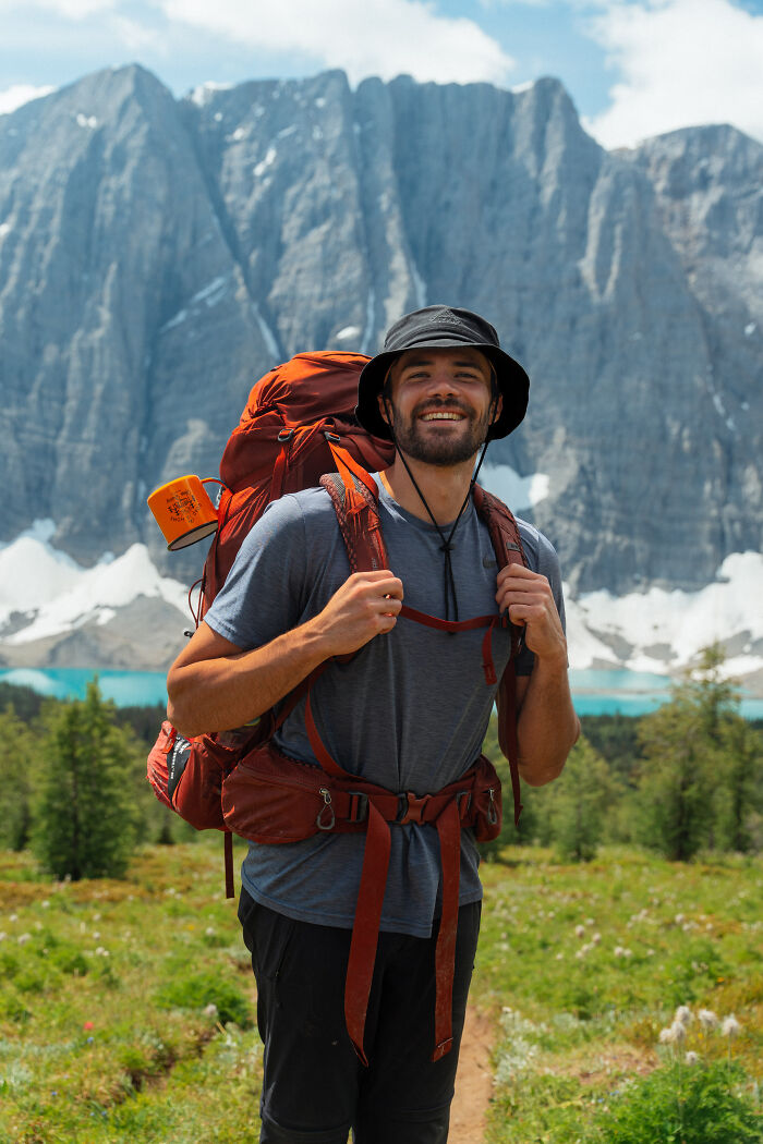 Hiker with a large backpack smiling on a trail, surrounded by mountains and nature, reflecting a journey to find purpose. Hiker with a large backpack smiling on a trail, surrounded by mountains and nature, reflecting a journey to find purpose.