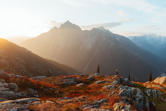 Hiker standing on rocky mountain ridge during sunrise, reflecting on purpose and personal journey in nature. Hiker standing on rocky mountain ridge during sunrise, reflecting on purpose and personal journey in nature.
