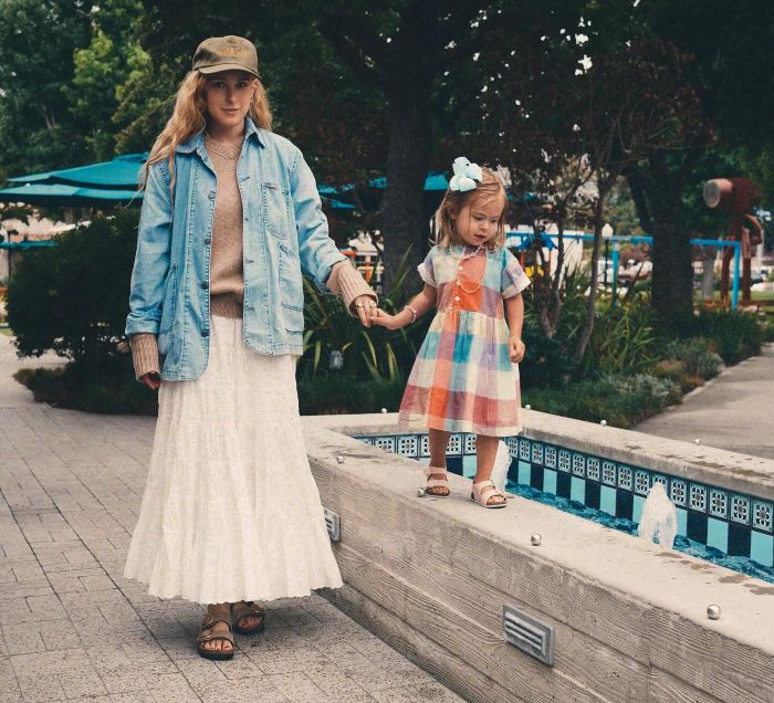 Bruce Willis' daughter and a young girl holding hands while walking near a fountain sharing dementia update. Bruce Willis' daughter and a young girl holding hands while walking near a fountain sharing dementia update.
