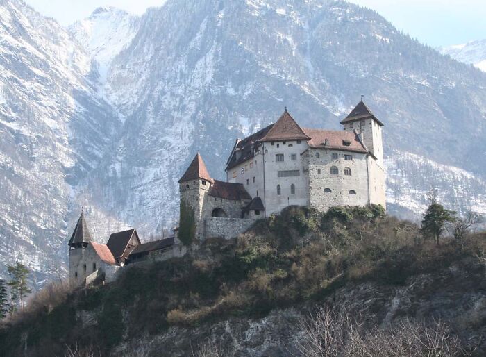 Medieval castle perched on a hilltop with snowy mountains in the background, showcasing a historical event setting.
