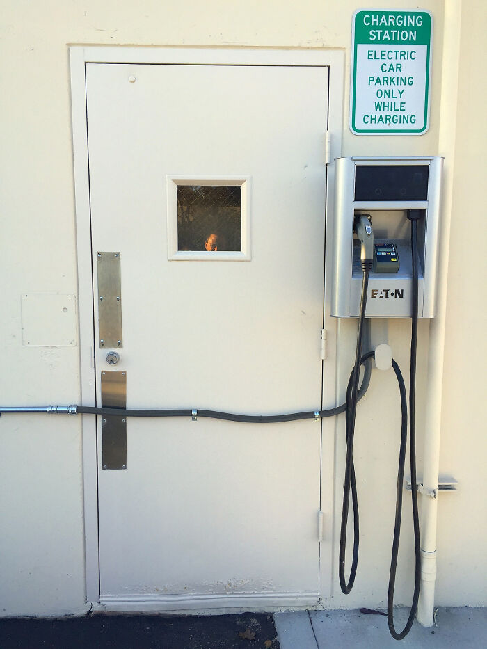 Electric car charging station with cable installed through a door, showing a funny example of people not even trying.