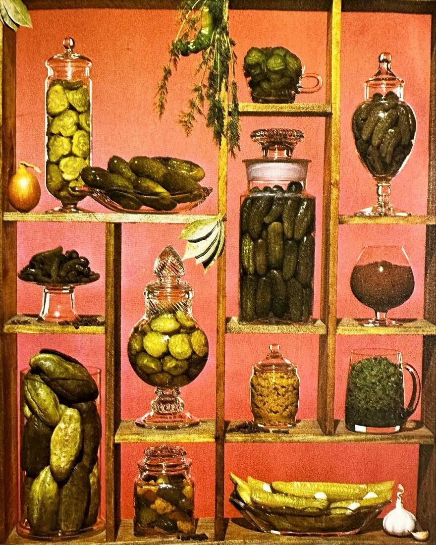 Vintage recipes featuring bizarre pickled vegetables displayed in glass jars on wooden shelves against a pink background.
