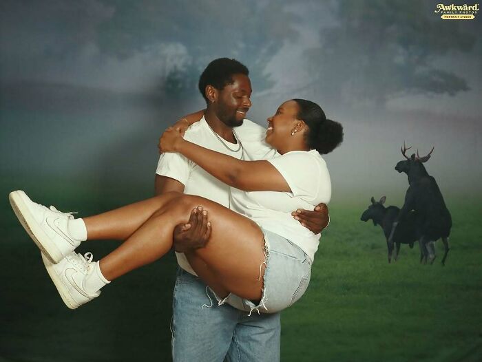 Couple posing in an awkward studio pic with an unusual moose background, creating a humorous and cringe-worthy moment.