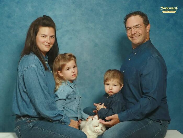 Family wearing denim outfits posing awkwardly in a studio with a white cat for an awkward studio pics photo session.