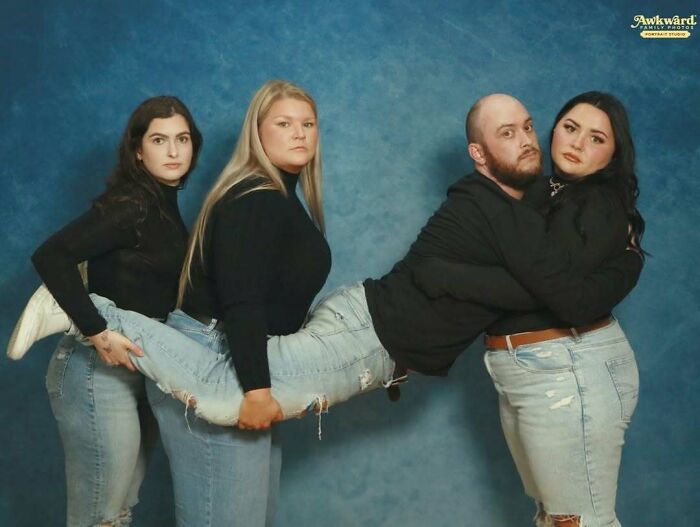 Four adults posing in an awkward studio pic, with one person horizontally held by three others laughing and smiling.