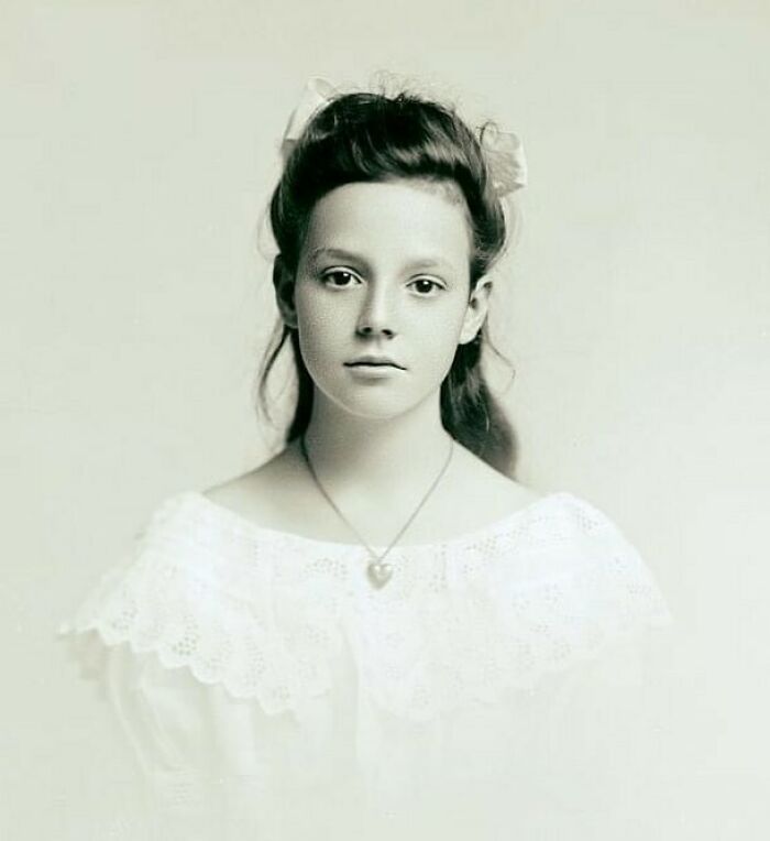 Victorian era portrait of a young girl in a lace dress with a heart-shaped pendant, showcasing weird photos from the Victorian era.