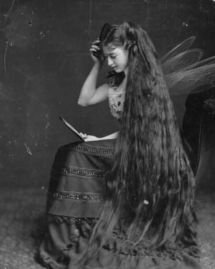 Victorian era woman with extremely long hair sitting and reading, showcasing the weird photos from the Victorian era.