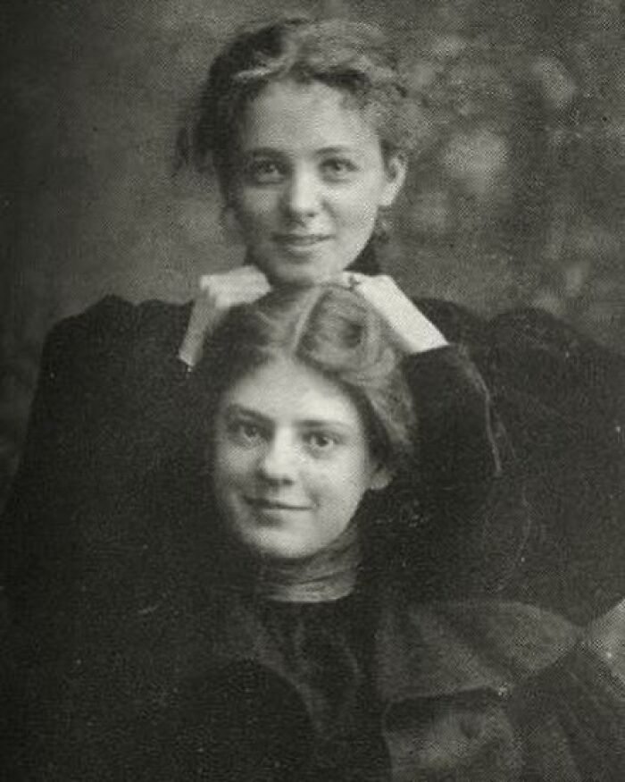 Two young women posing for a black and white portrait, showcasing fashion and style from the Victorian era.
