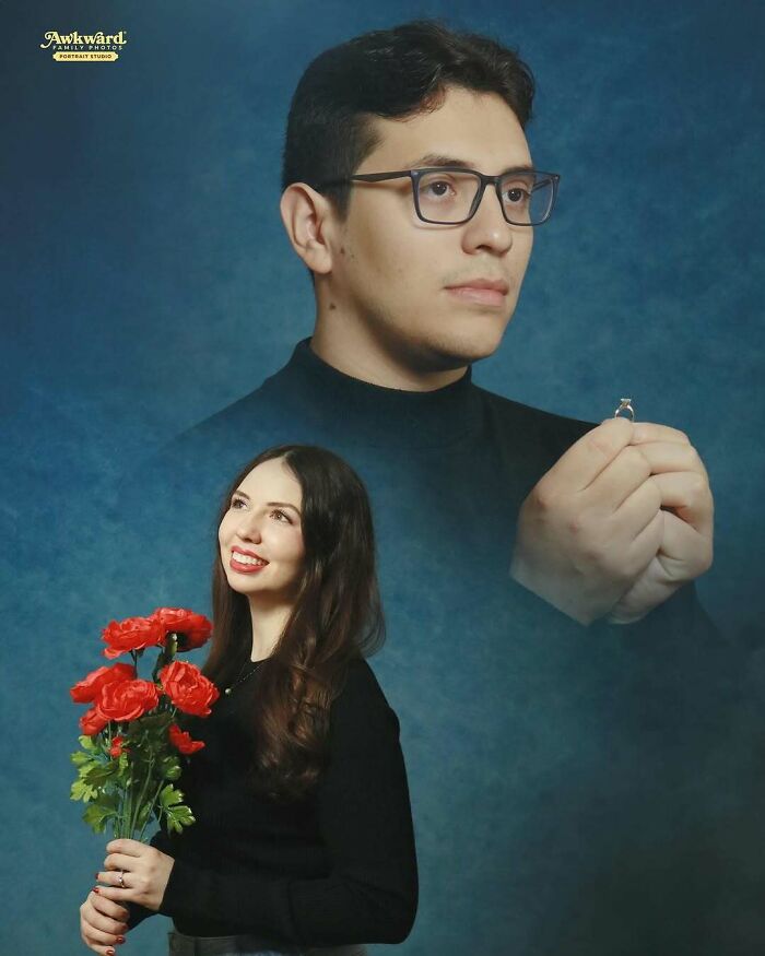 Man holding a ring and woman holding flowers in an awkward studio photo with a blue background and black outfits.