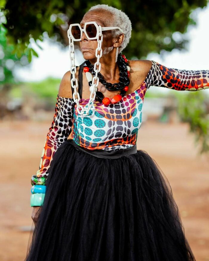 Elderly woman wearing colorful patterned top and unique accessories, embodying viral internet icon style.