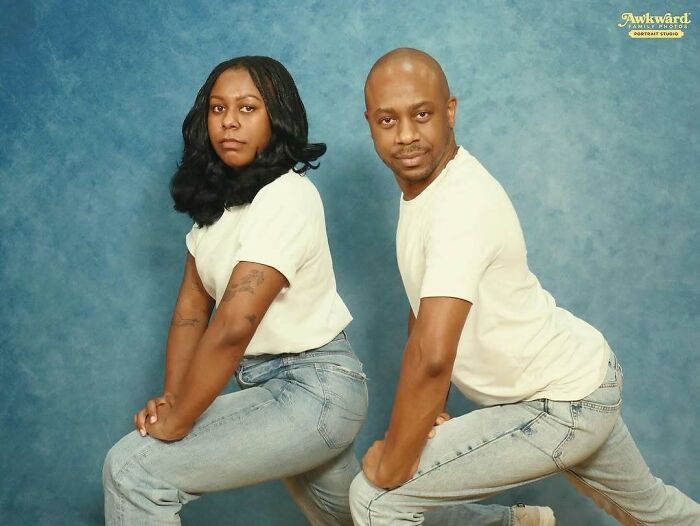 Couple posing awkwardly in a studio photo with matching white shirts and jeans against a blue backdrop.