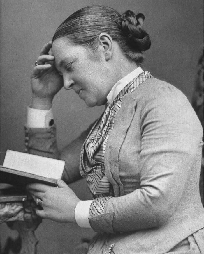 Black and white photo of a thoughtful woman reading a book, representing overlooked women in history and their achievements.
