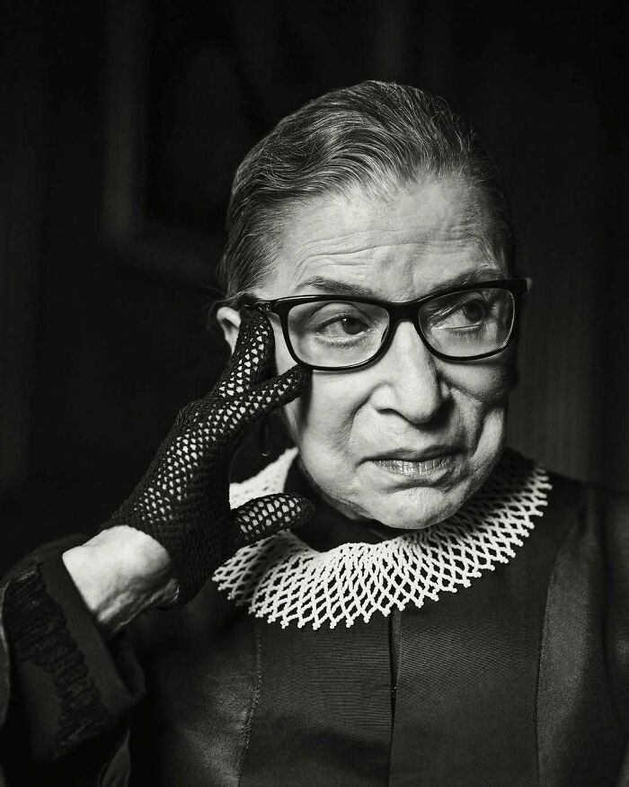 Black and white portrait of a woman wearing glasses and lace gloves, representing overlooked women in history and achievements.