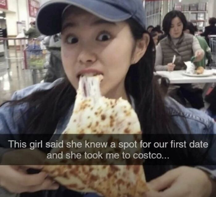 Young woman eating large cheesy pizza slice at Costco, funny meme highlighting a unique first date spot.