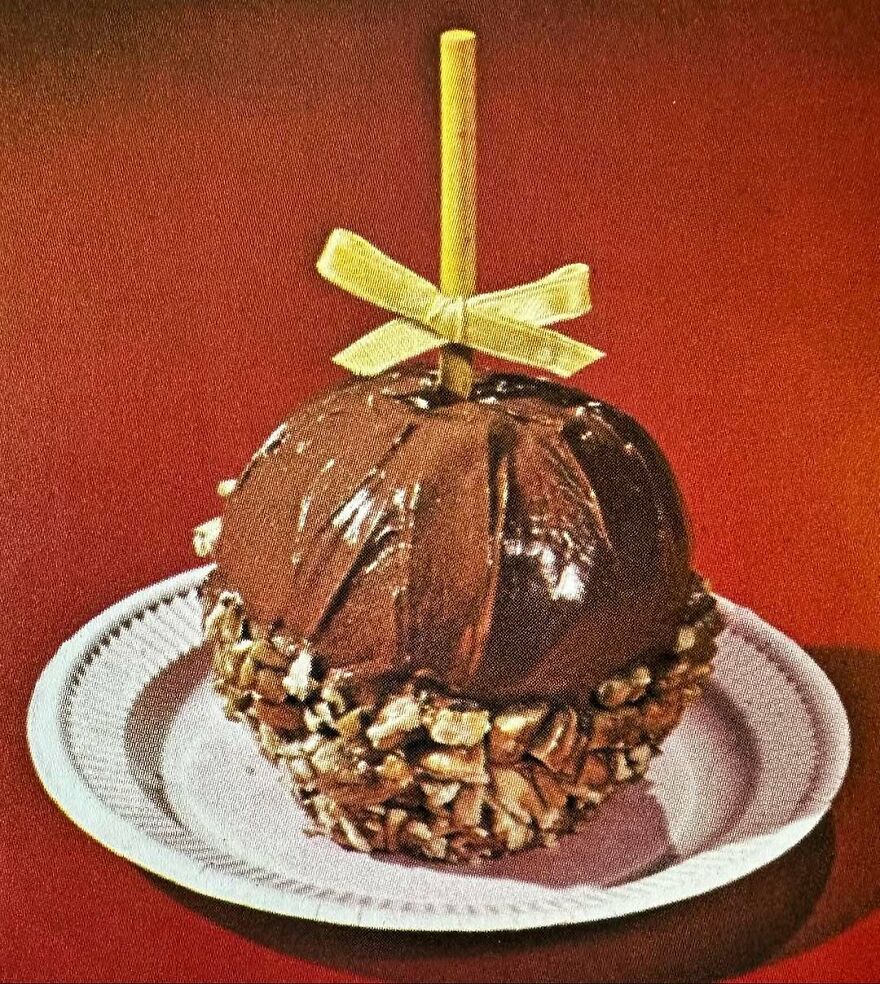 Vintage chocolate-covered apple with nuts on a white plate, showcasing bizarre vintage recipes and unique dishes of the past.