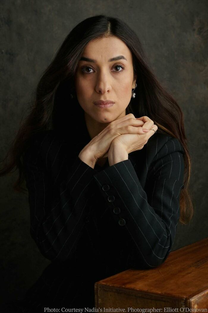 Woman in a pinstripe blazer posing thoughtfully, representing overlooked women in history and their important achievements.