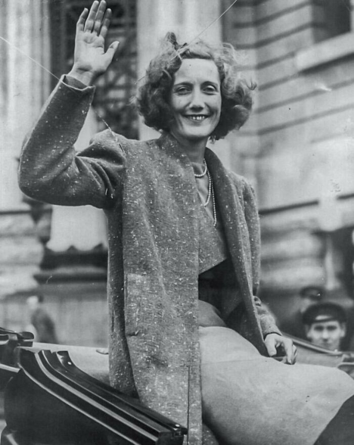 Black and white photo of a woman smiling and waving, representing overlooked women in history and their achievements.