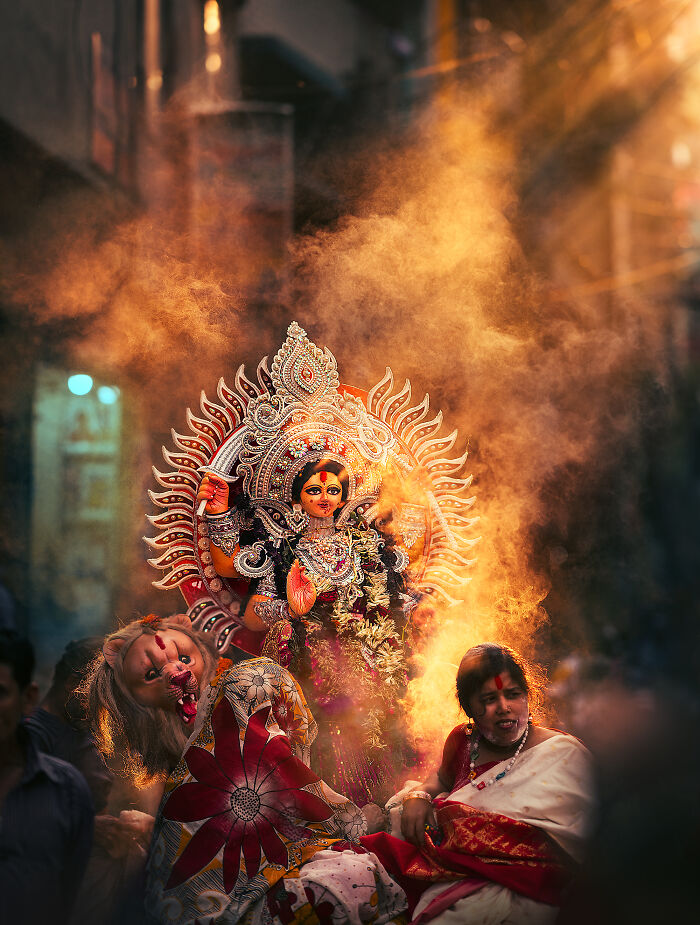 Vibrant street photography capturing a cultural festival with colorful costumes and dramatic light and smoke effects.