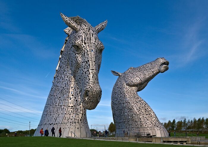 Two spectacular large horse head sculptures made of metal plates outdoors under a blue sky, a top travel sculpture attraction.