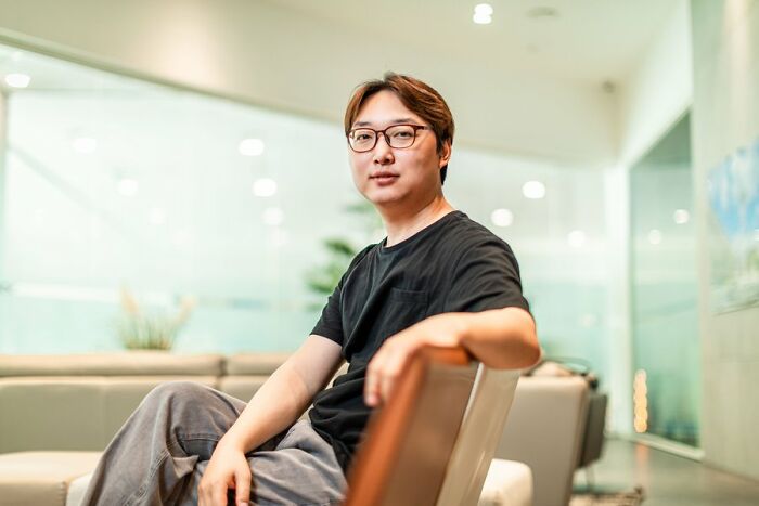 Portrait of South Korea’s smartest man sitting casually in a modern room, looking confidently toward the camera. Portrait of South Korea’s smartest man sitting casually in a modern room, looking confidently toward the camera.