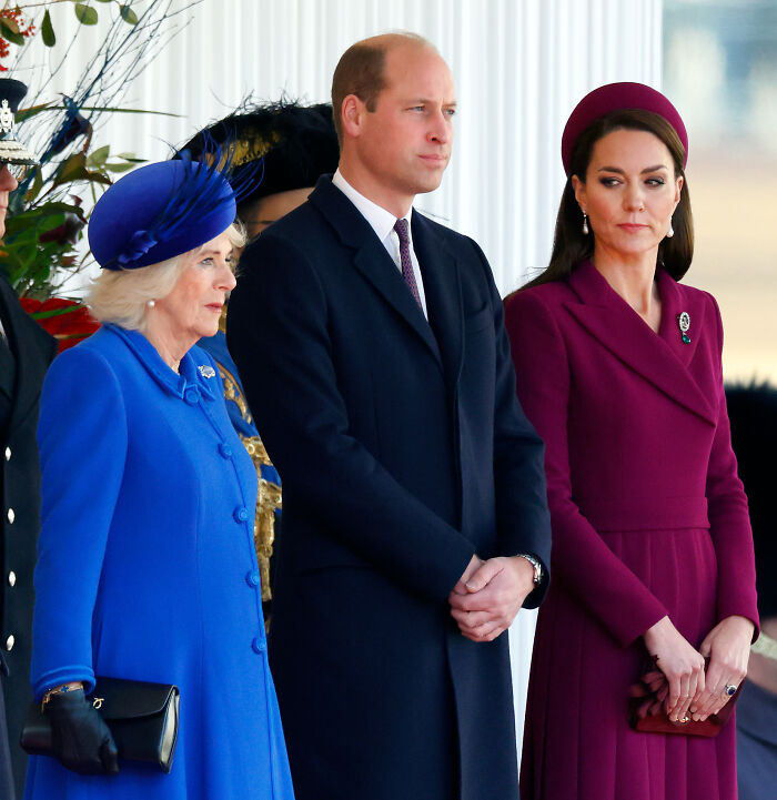 Kate Middleton and Queen Camilla standing together, dressed formally, reportedly influencing Andrew’s title removal decision.