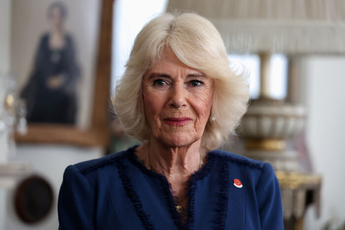 Queen Camilla wearing a blue outfit indoors, reflecting the female touch influencing Andrew’s title removal decision.