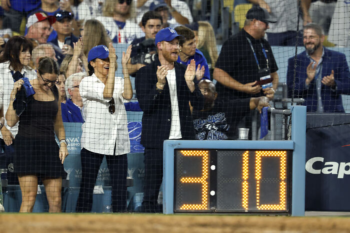 Prince Harry and Meghan Markle celebrating at a baseball game, sparking many to think the event was staged. Prince Harry and Meghan Markle celebrating at a baseball game, sparking many to think the event was staged.
