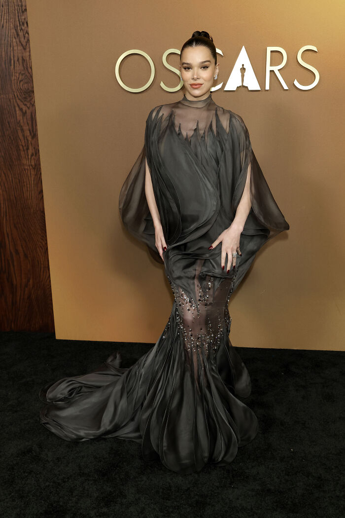 Woman in a sheer black gown with embellishments posing at a fashion event, highlighting Governors Awards fashion disasters.