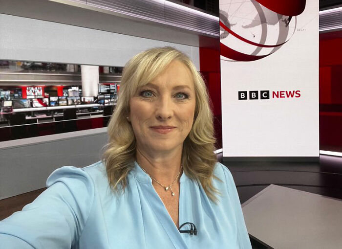 BBC anchor in a newsroom wearing a blue shirt, associated with news on discipline related to trans remarks on-air. BBC anchor in a newsroom wearing a blue shirt, associated with news on discipline related to trans remarks on-air.