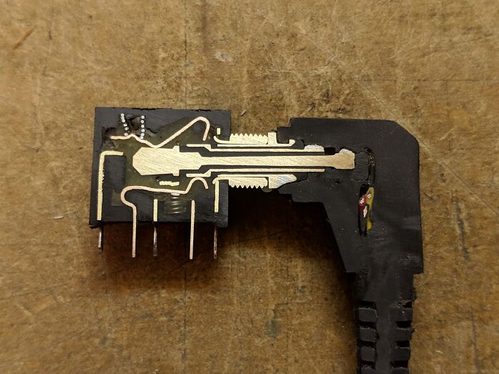 Close-up of the insides of an electronic component showing detailed circuits and metal contacts, revealing unseen object parts.