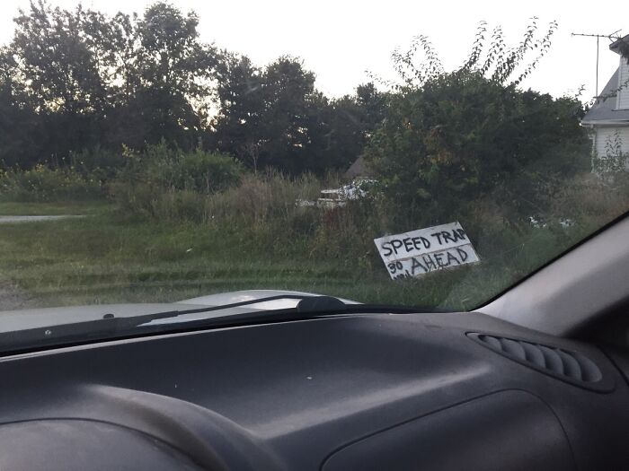 View from inside a car showing a handmade sign warning of speed trap ahead, illustrating strangers helping each other.