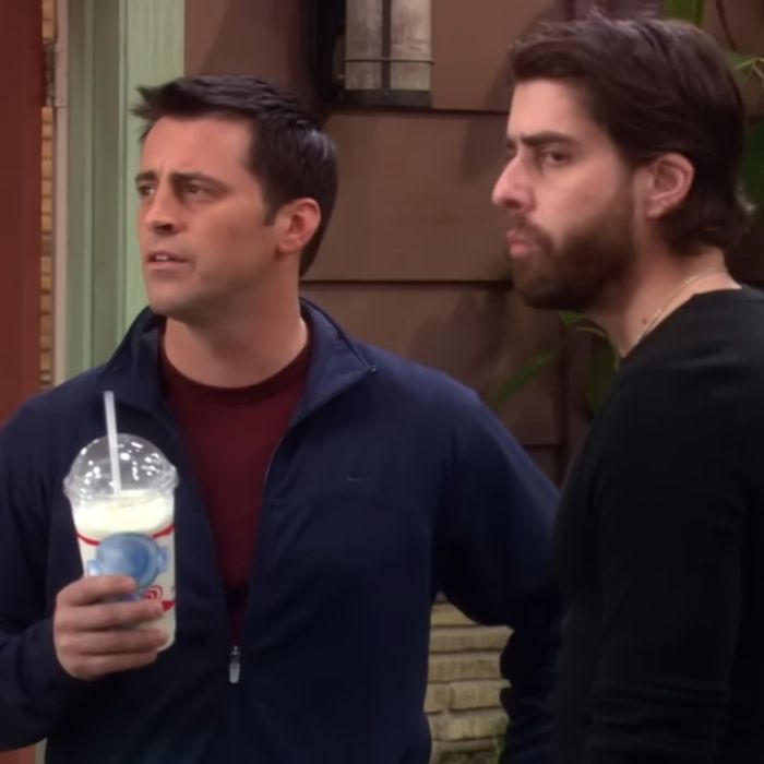 Matt LeBlanc as Joey in unaired episodes, standing outdoors with a drink, wearing a navy jacket and maroon shirt.