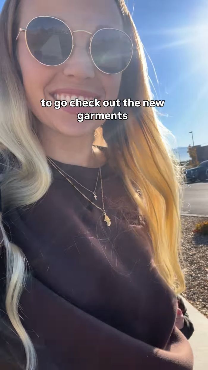 Smiling woman outdoors wearing sunglasses and necklaces, excited about more revealing sacred underwear garments.