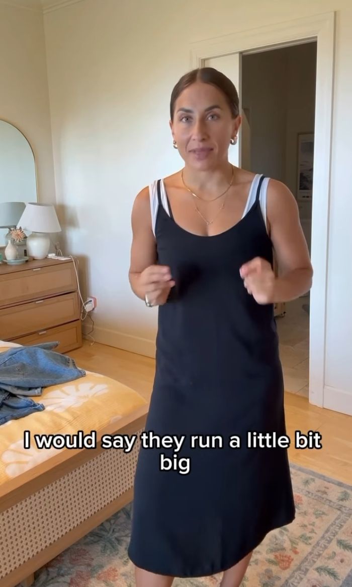 Woman in a black dress discussing Mormon women’s reaction to more revealing sacred underwear in a casual bedroom setting.