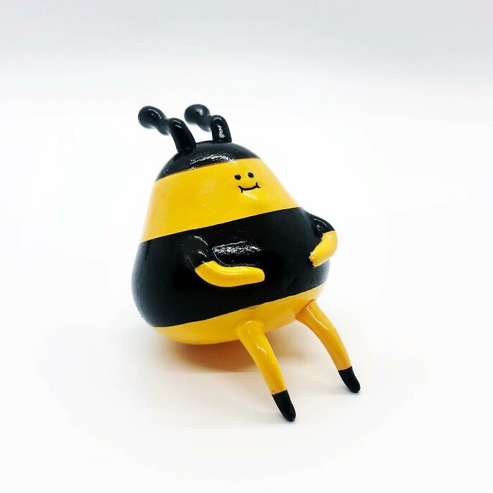 Quirky sculpture of a smiling bee with bent legs and antennae, bursting with personality in bright yellow and black.