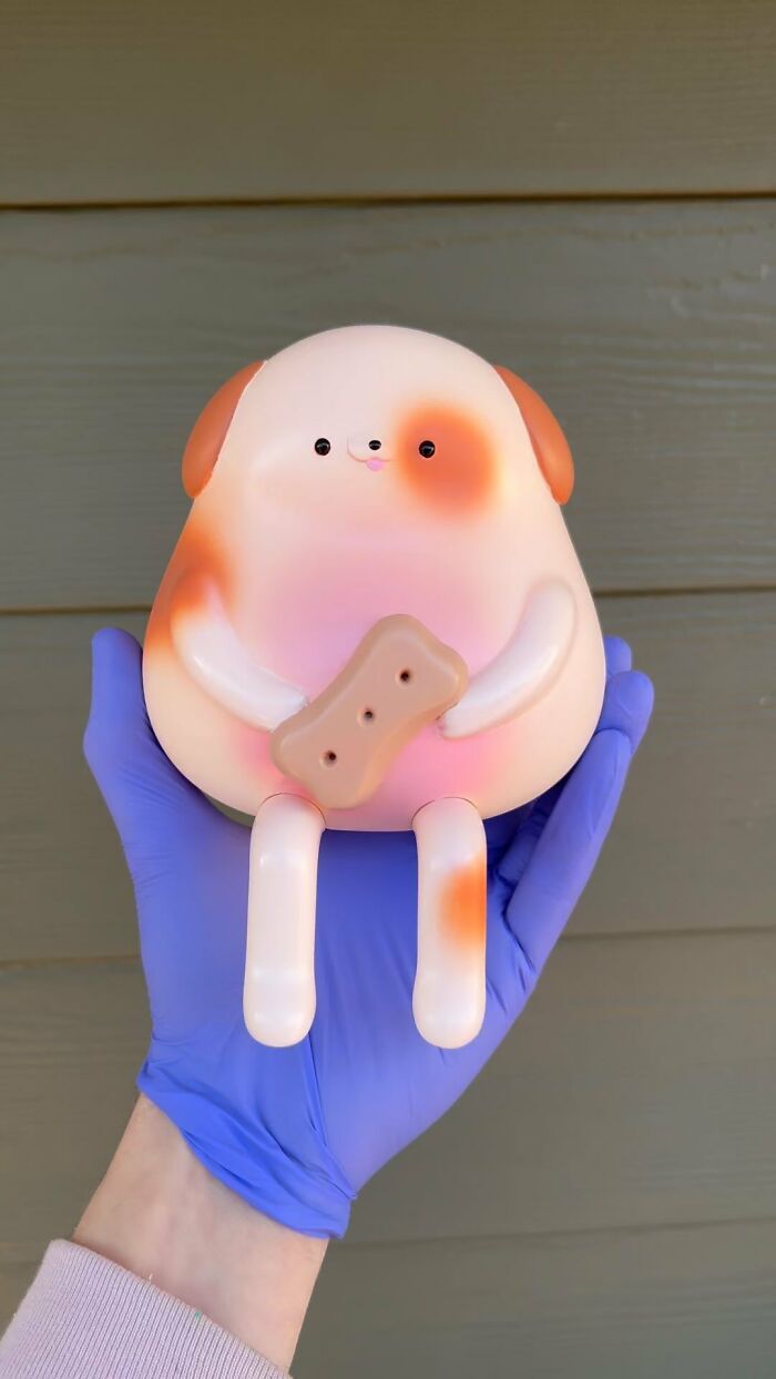 Hand holding a quirky dog sculpture with a bone, showcasing artist made quirky sculptures bursting with personality.