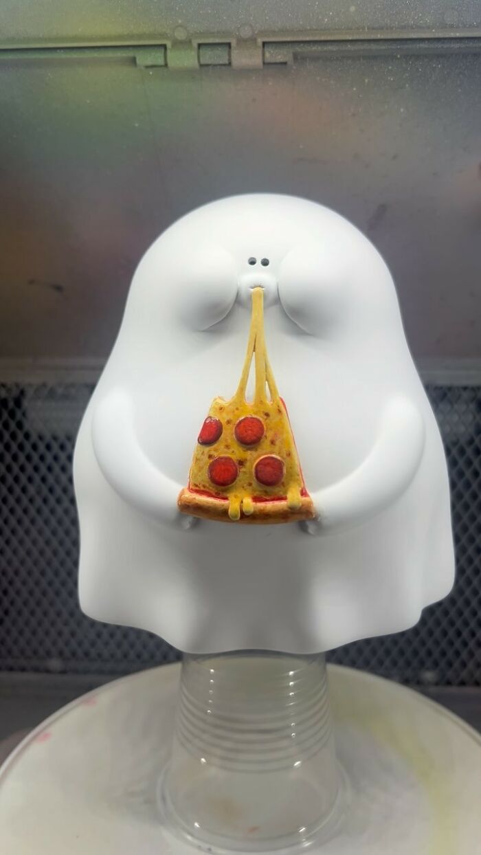 White quirky sculpture with personality holding a slice of pepperoni pizza with melted cheese stretching from its mouth.