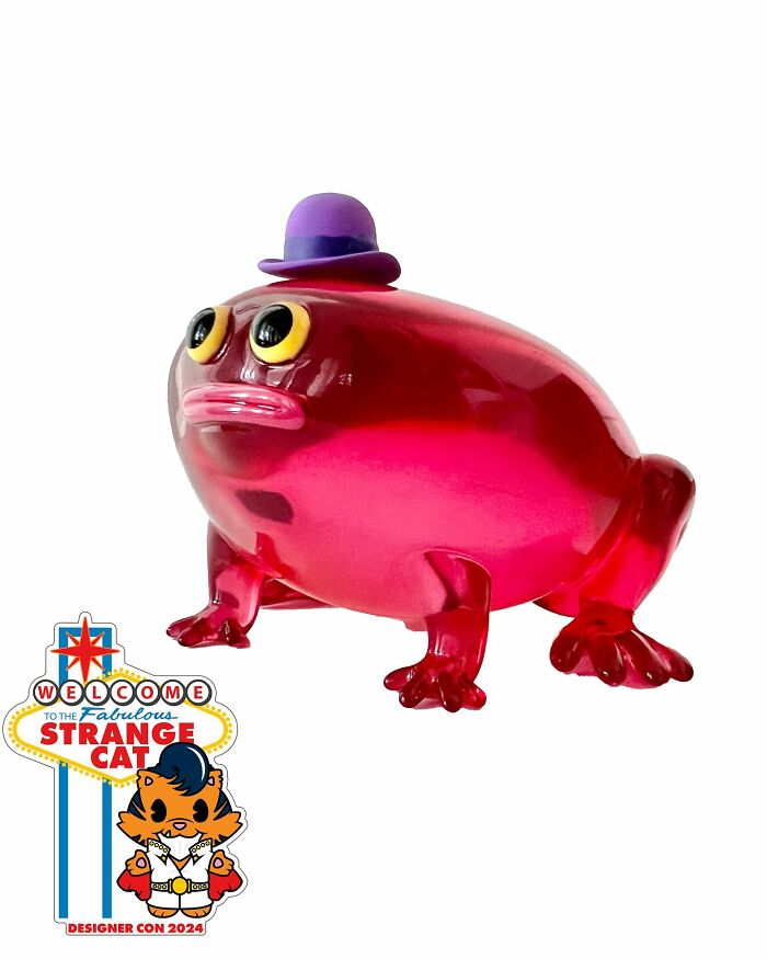 Red quirky sculpture of a frog wearing a purple hat, showcasing artist-made personality-filled design.