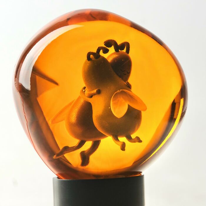 Amber sculpture featuring two quirky bee characters hugging, showcasing artist made quirky sculptures bursting with personality.