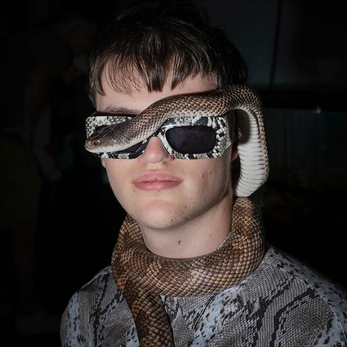 Young man and his snake wearing matching patterned clothing and glasses, showing pets and humans that look alike.
