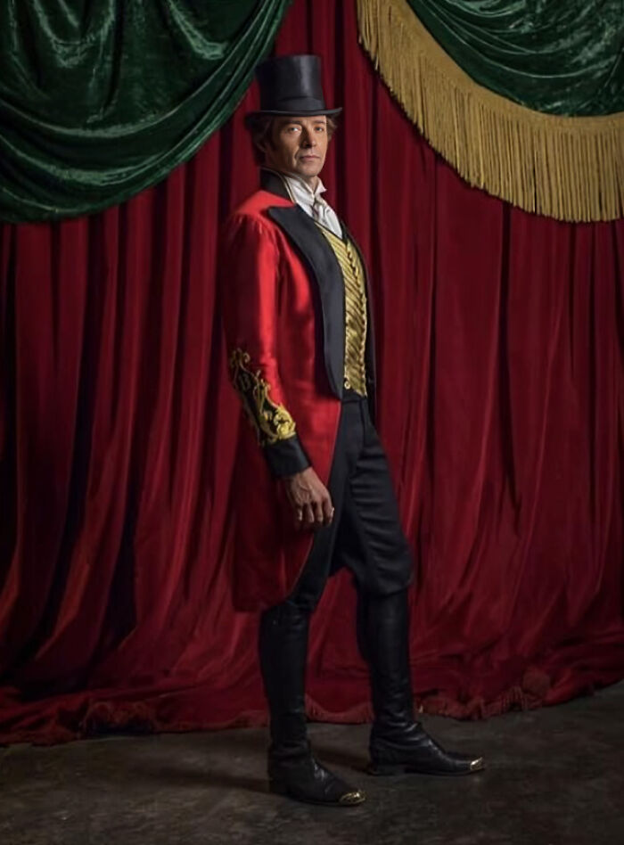 Man in vintage circus ringmaster costume with top hat standing against a red velvet curtain bizarre moments