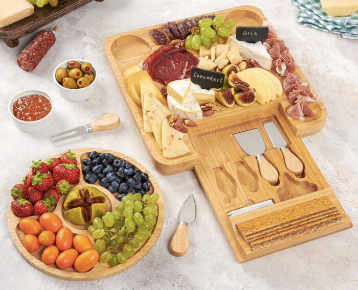 Bamboo cheese board and fruit platter with knives, grapes, strawberries, and assorted cheeses for foolproof gift finds.