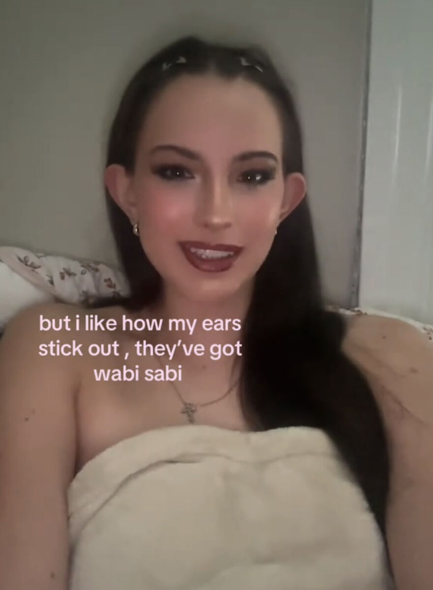 Young woman with makeup smiling and embracing her perfect imperfections of ears that stick out in a wholesome trend.