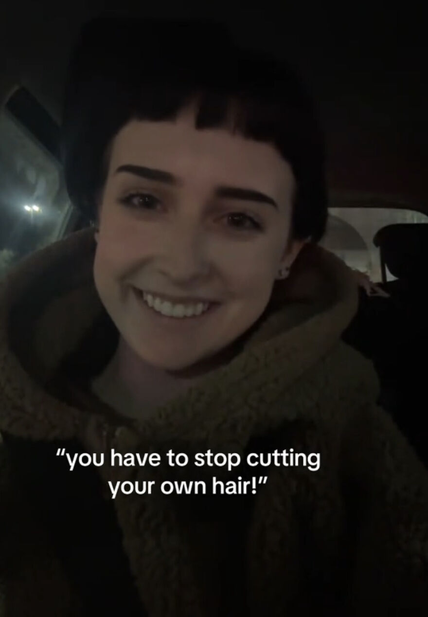 Smiling person with short uneven bangs in a cozy jacket, sharing a perfect imperfection in this wholesome trend.