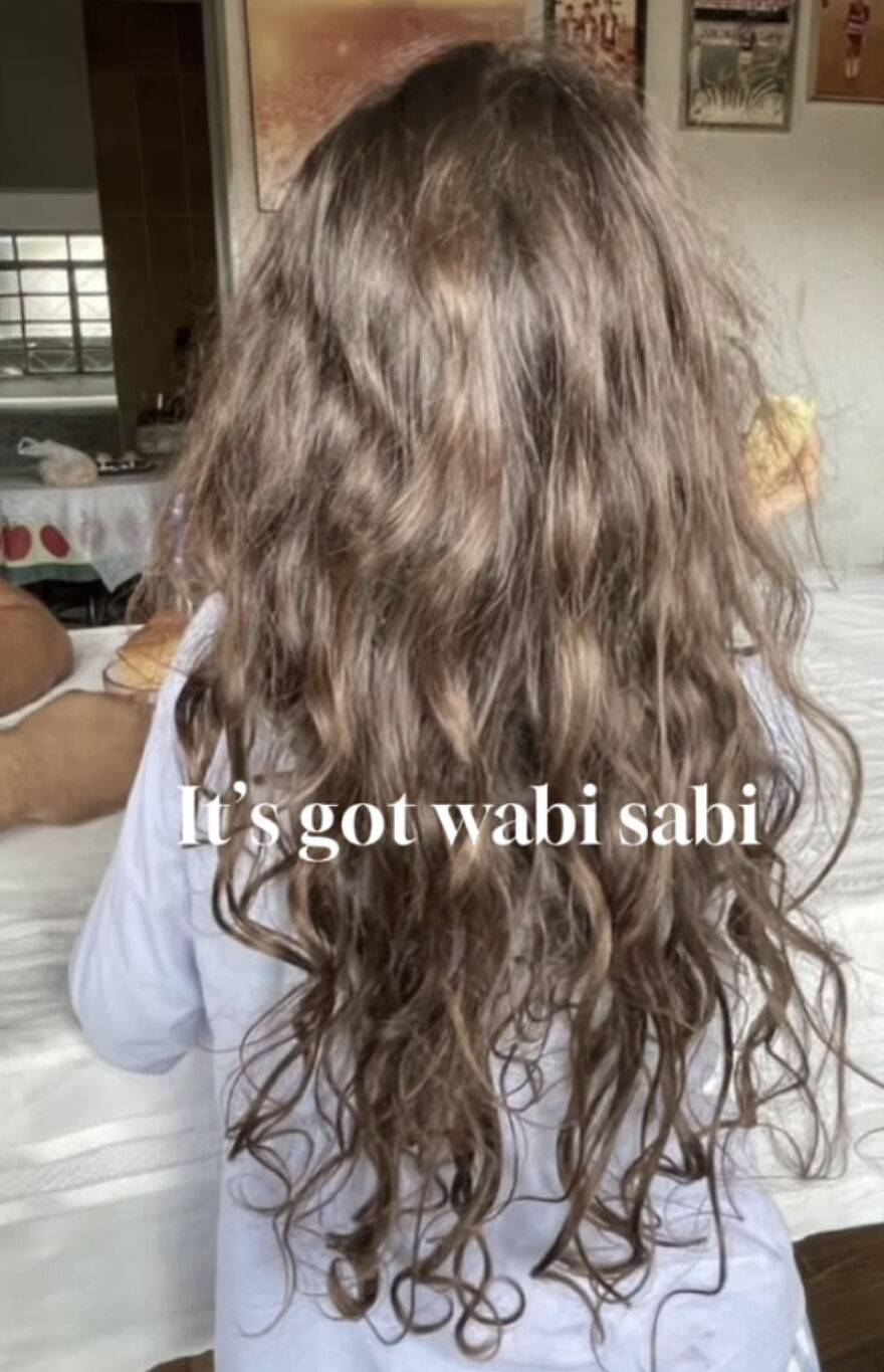 Person with long curly hair showcasing perfect imperfections in a wholesome trend embracing natural beauty and wabi sabi.